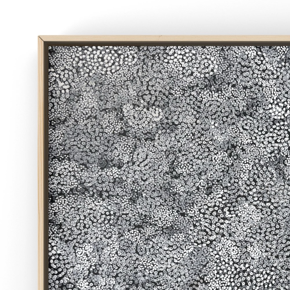 Corner detail of Thousand Dots 1, showing the pale wood frame meeting the painted field of dots.