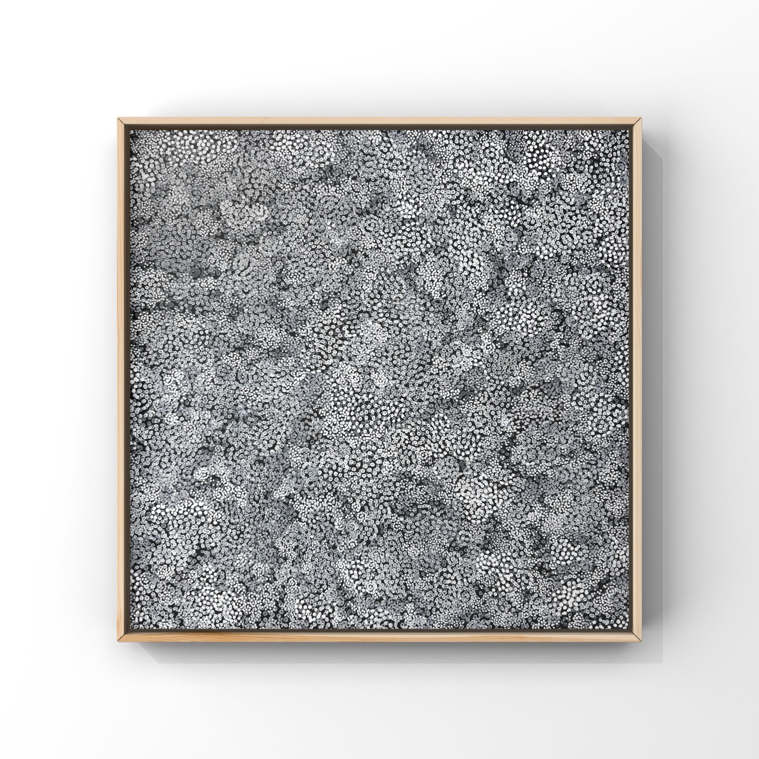 Thousand Dots 1 &mdash; a square painting, a dense field of thousands of small white and gray hand-painted dots on black, in a pale wood frame on a white wall.